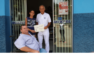 Nilcei, da Mixpel, entregando a Wemwerson junto de Vicente Medina, coordenador do sorteio, R$ 5 mil 