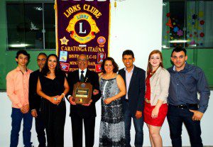 Ladeado por familiares, Sebastião Gomes Zeferino apresenta a homenagem concedida pelo Lions Clube Caratinga Itaúna 