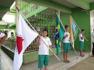 Alunos carregam as bandeiras de Minas, do Brasil e do Município 